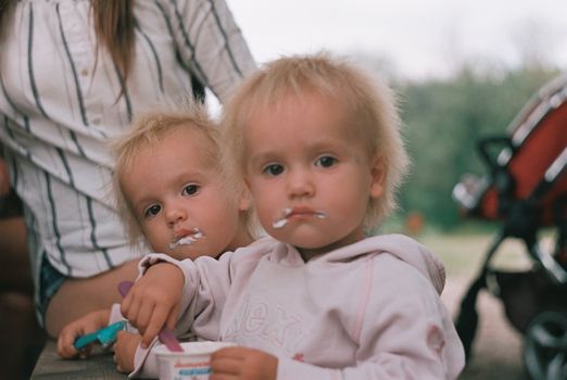 Two cute toddlers enjoying ice cream outdoors, creating a playful and joyful scene.