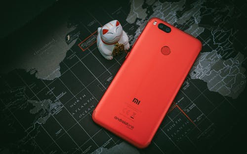 3348: Free Red Xiaomi Mi Smartphone Beside White Cat Figurine Stock Photo