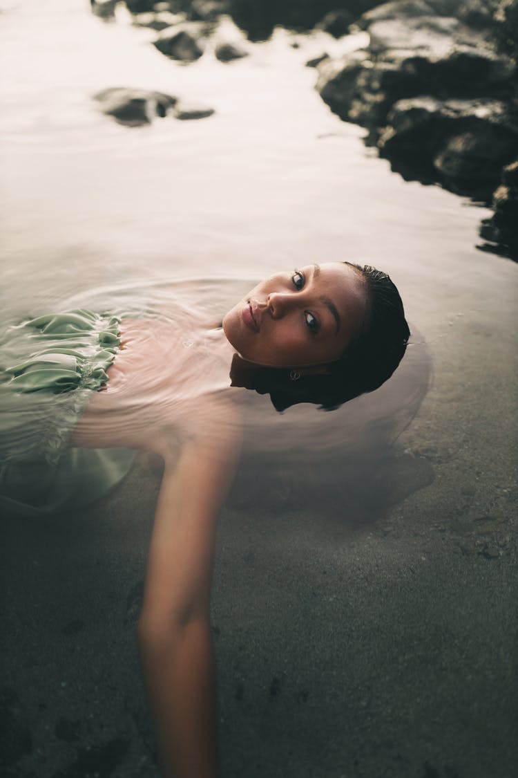 A Woman In A Green Dress Floating On The Water