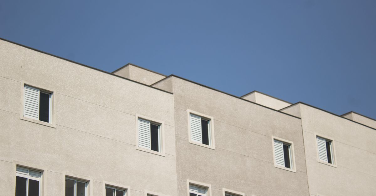 Minimalist urban building design with a focus on concrete facade and windows under a clear blue sky.
