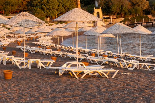 Free Sunlit beach with empty lounge chairs and umbrellas, perfect for a tranquil summer getaway. Stock Photo