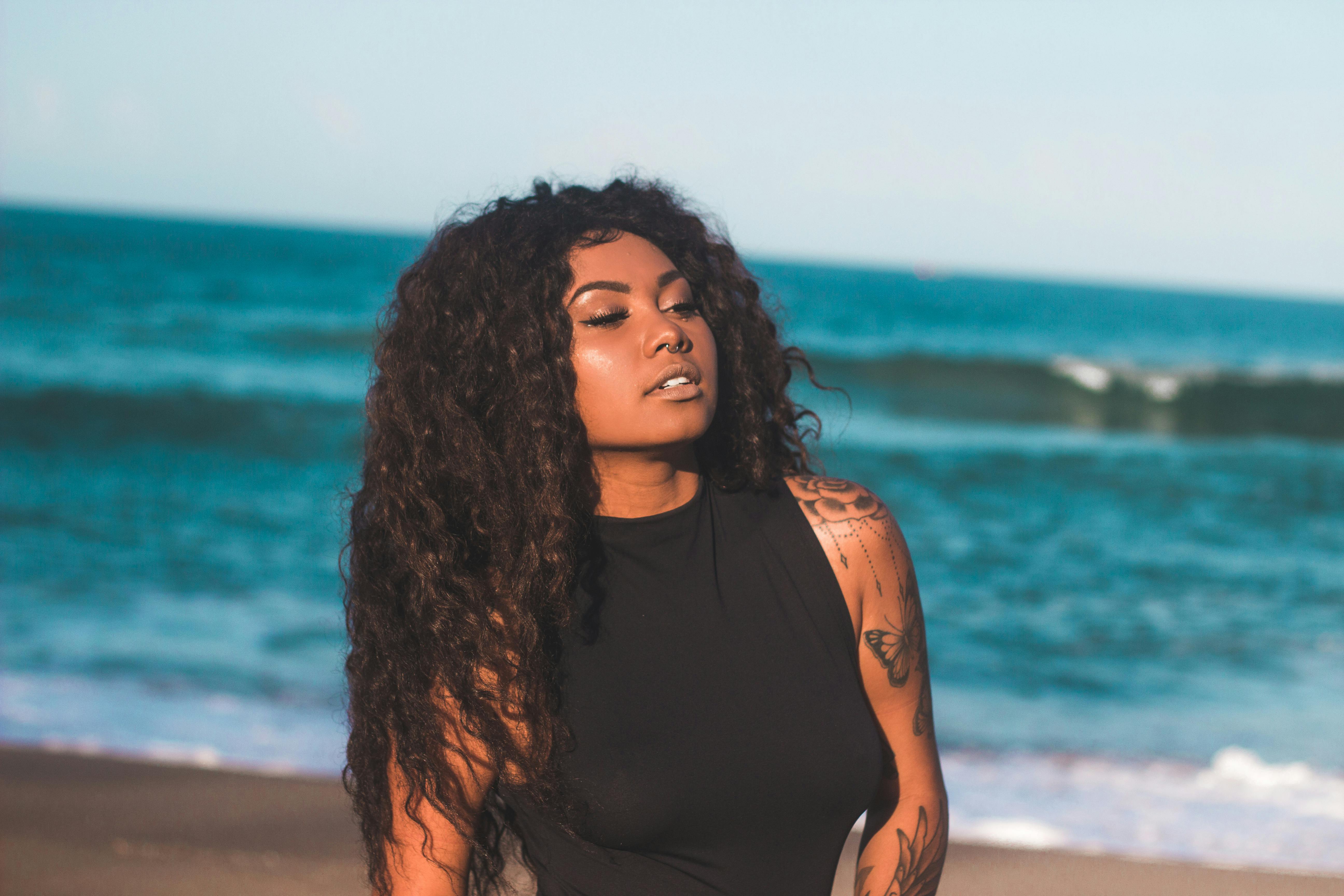 close up photo of a beautiful woman with curly hair and a nose piercing