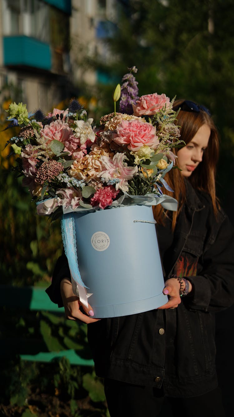 A Woman Carrying A Bucket With Flowers