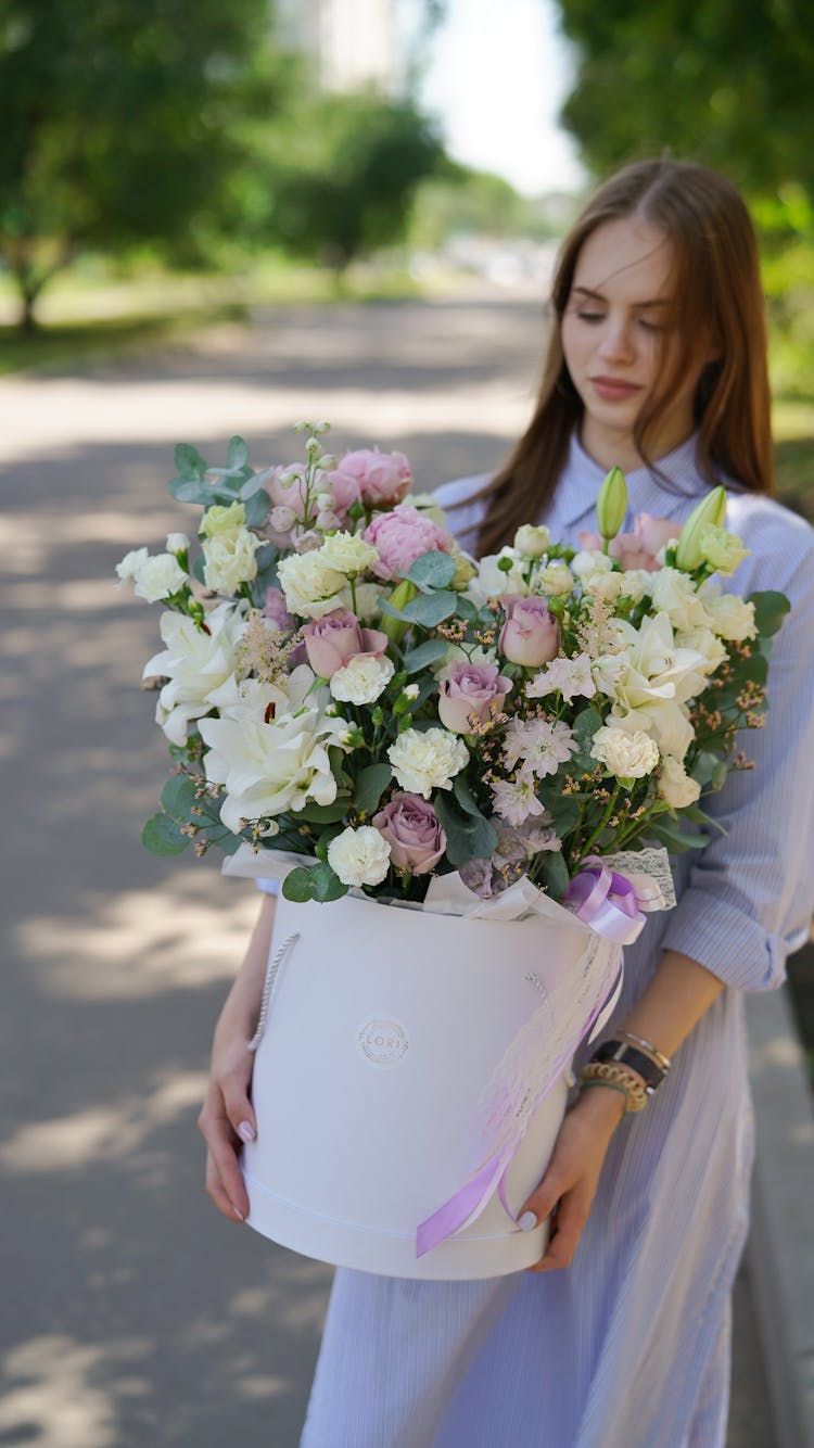 A Woman Carrying A Bucket Of Flowers