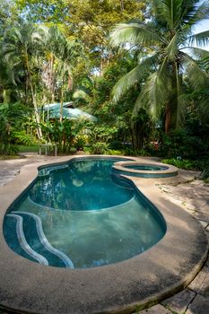 Relaxing tropical poolside setting in lush Costa Rican garden.