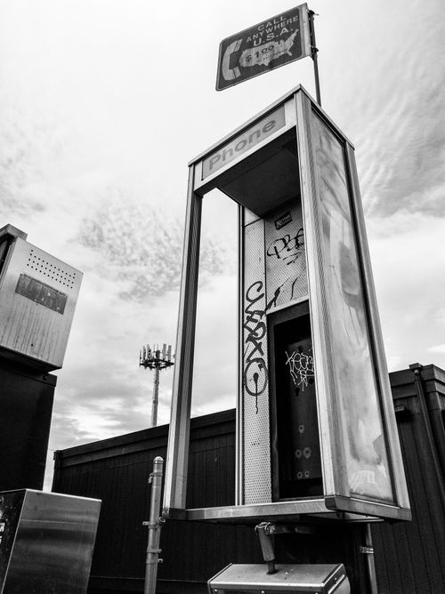 Free Vintage payphone booth with graffiti in a cityscape, captured in black and white. Stock Photo