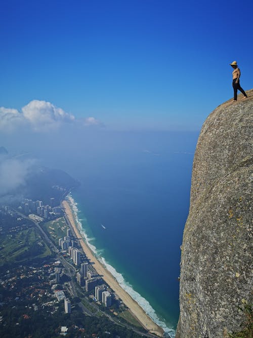 Free Man Standing on Rock Formation Under the Blue Sky Stock Photo
