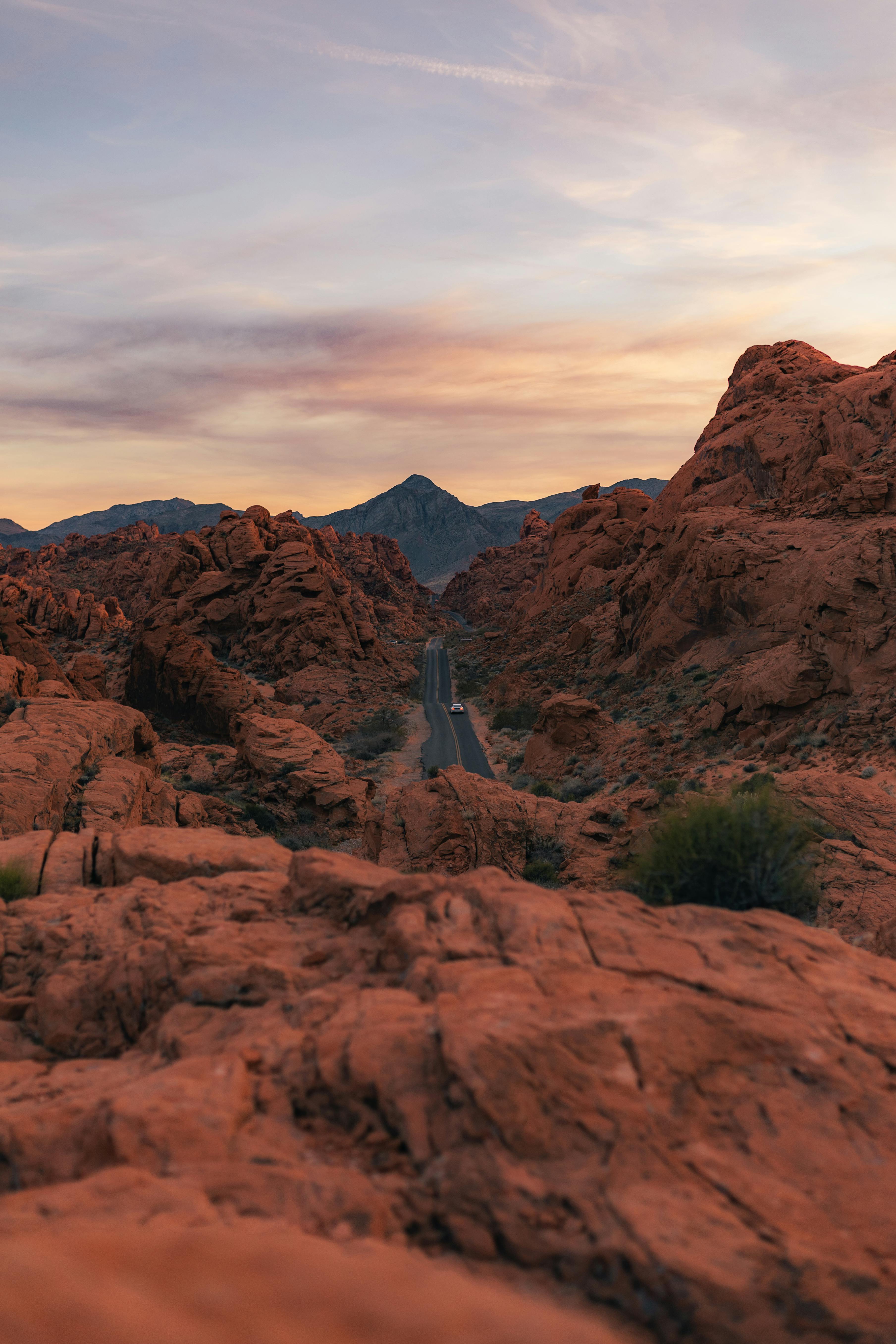A breathtaking view of a winding road through Nevada's red rock desert at sunset.