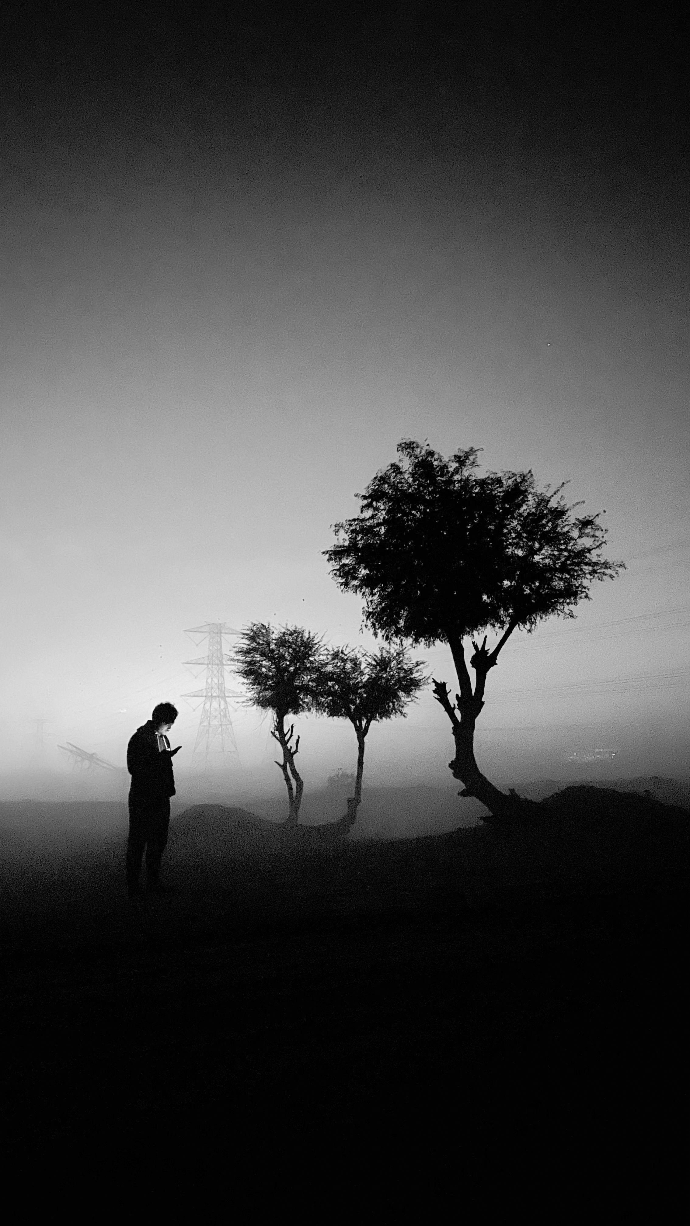 A moody black and white silhouette of a man in a foggy evening landscape, Dubai.