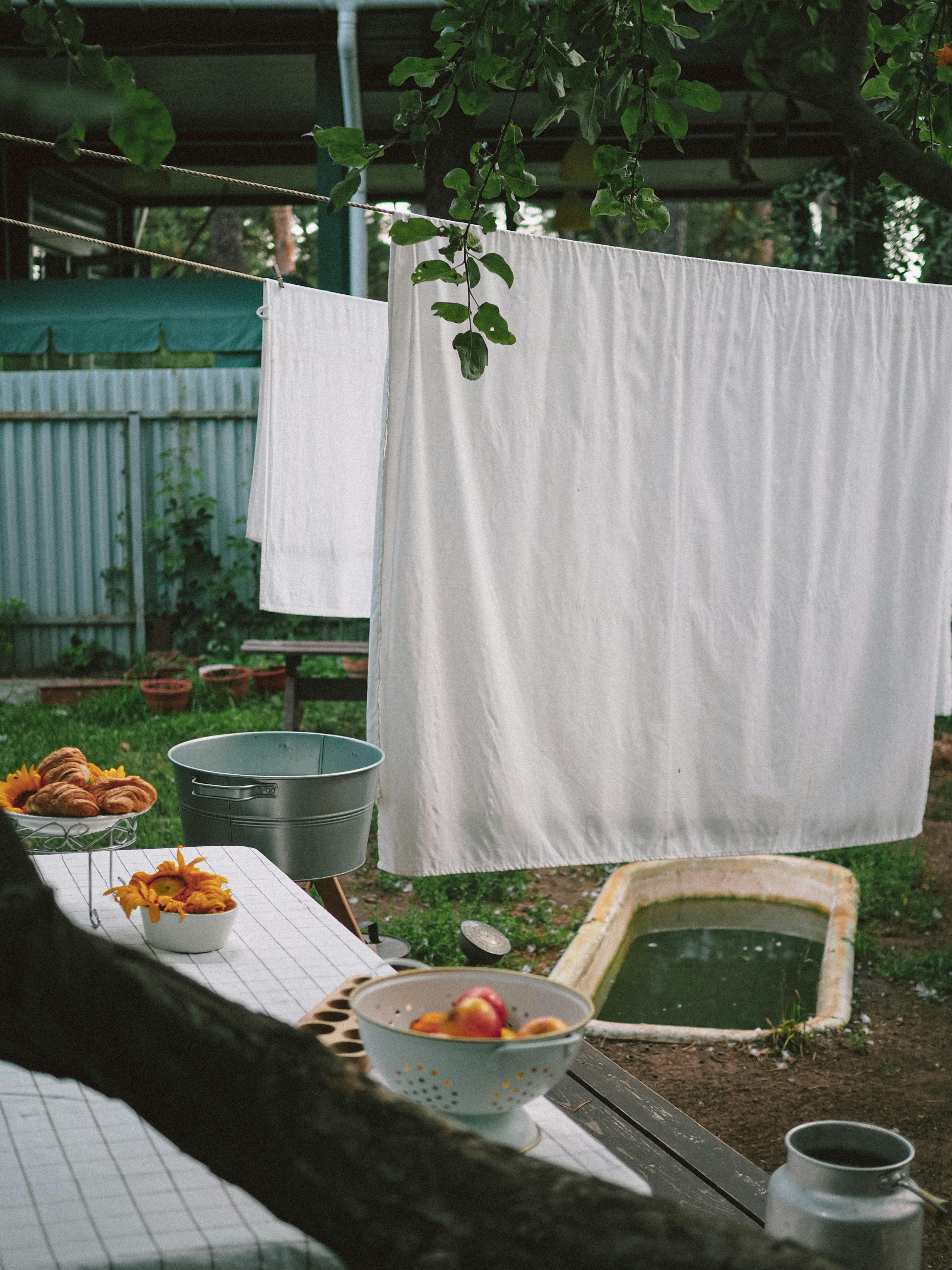 A charming outdoor setup featuring drying laundry, fresh fruit bowls, and a serene garden ambiance.