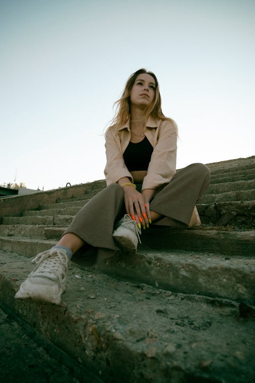 Free Woman in Brown Long Sleeve Shirt Sitting on Concrete Steps Stock Photo