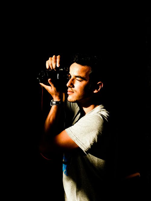 Free Close-up portrait of a photographer in dark moody lighting with a DSLR camera. Stock Photo