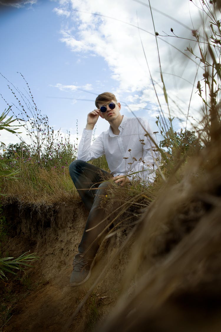 A Man In White Polo Long Sleeves Projecting On  The Camera  While Sitting On A Grass Field