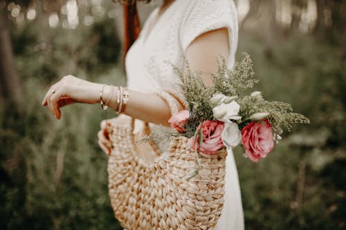 A Woman Carrying Woven Hand Bag with Colorful Flowers in it