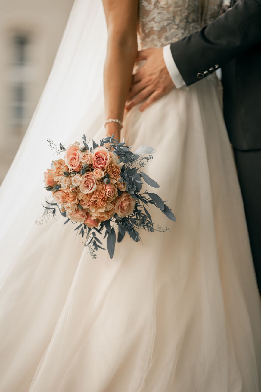 Close-up of a bride elegantly holding a pink floral bouquet on her wedding day.