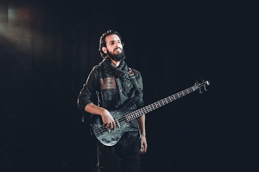 Musician with beard holding a bass guitar on stage, exuding confidence and style.