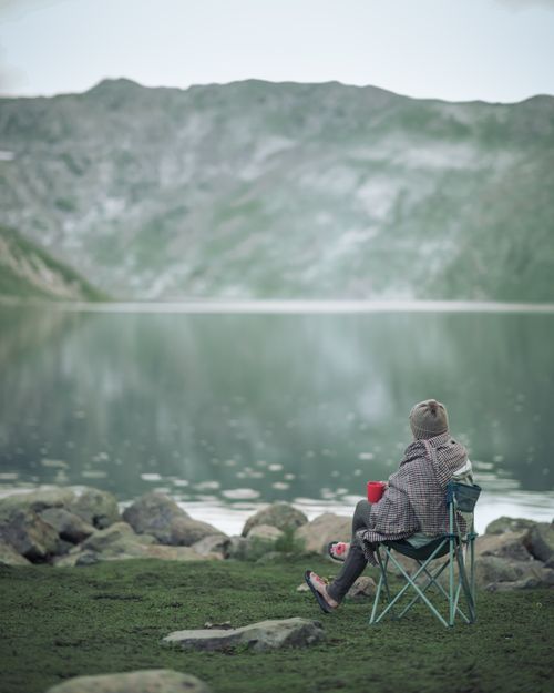 Free Person enjoying solitude by a tranquil mountain lake, capturing nature's beauty. Stock Photo