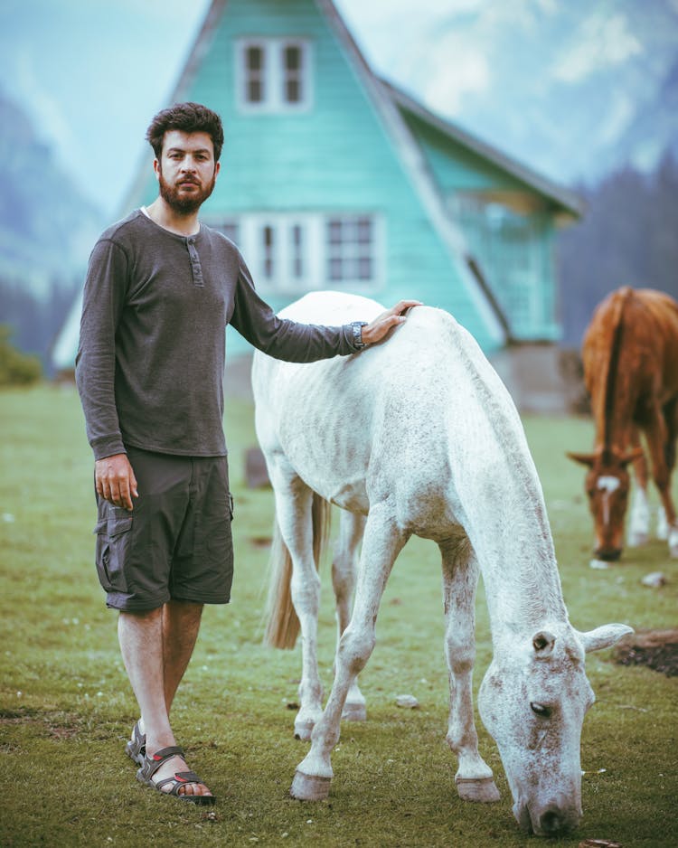 Bearded Man Standing Beside A White Horse