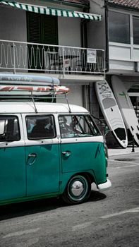 Turquoise vintage van with surfboards parked near a Croatian beach, ideal for travel adventures.