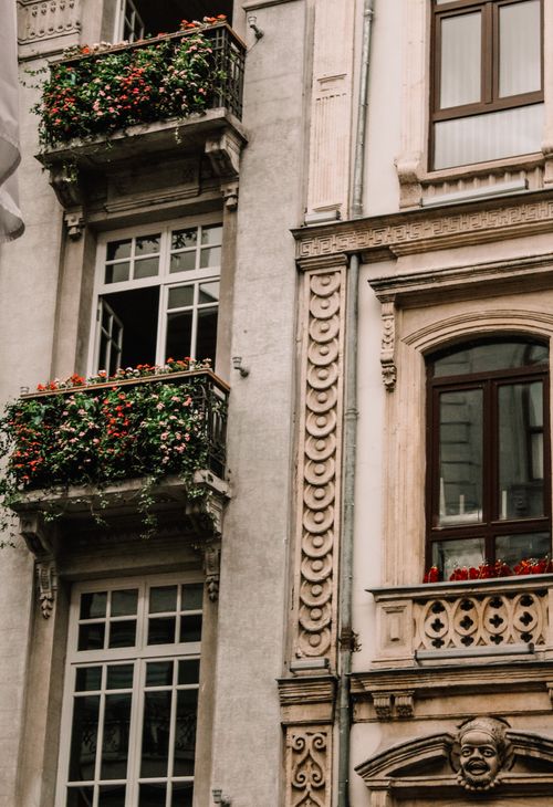Free A close-up of ornate building facade featuring balconies adorned with flowers, showcasing intricate urban design. Stock Photo