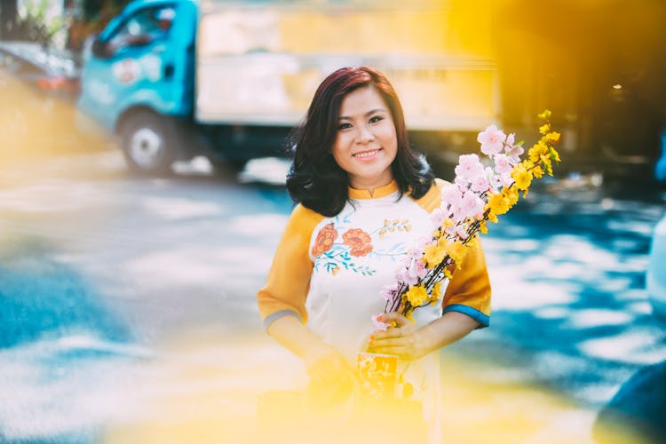 Blue And Yellow Toned Image Of A Woman Holding Flowers And Truck In Background