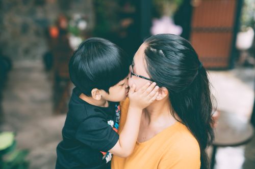 Free A heartwarming moment as a young boy kisses his mother on the cheek. Stock Photo