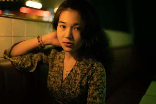 Free Charming portrait of a woman in a floral dress with warm lighting indoors. Stock Photo