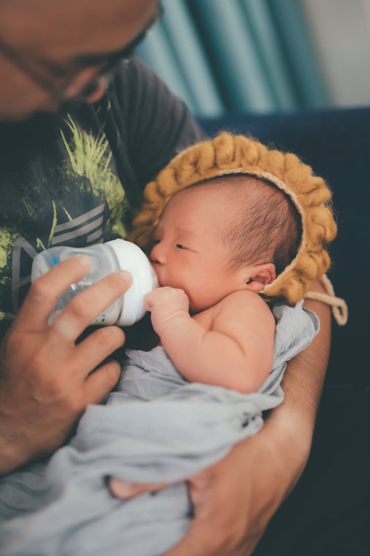 A Newborn Baby Drinking Milk From Feeding Bottle