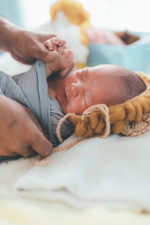 Free Tender moment capturing a newborn baby being gently swaddled in soft blankets. Stock Photo