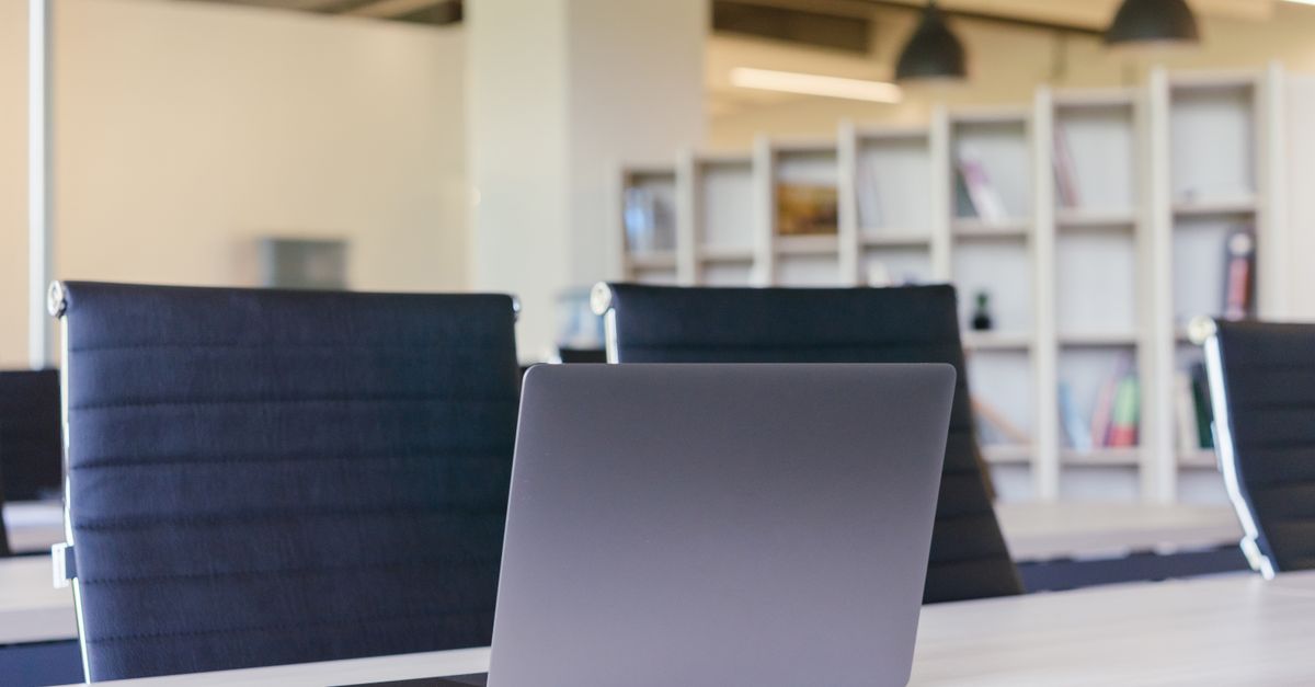 Contemporary office interior with a sleek laptop on a desk and stylish chairs.