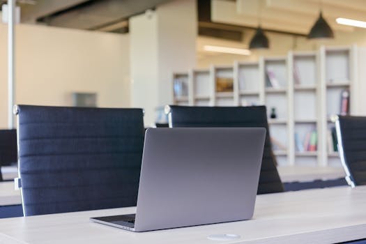 Contemporary office interior with a sleek laptop on a desk and stylish chairs.