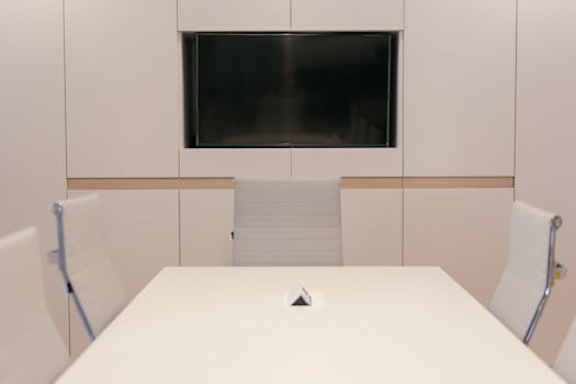 A modern conference room featuring sleek design with white furniture and technology setup.