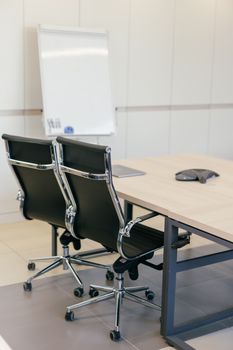 Contemporary office meeting room with black chairs, table, and whiteboard. Ideal for business settings.