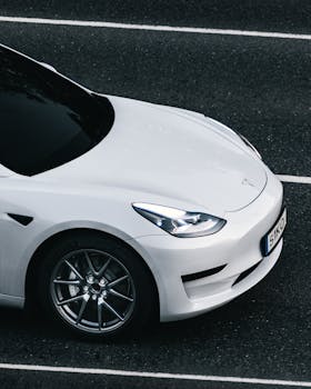 Top view of a sleek white Tesla electric car driving on a city street in Germany.