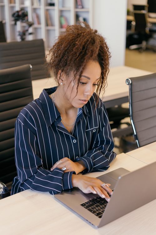 Free Professional woman using a laptop in a modern office, emphasizing technology and productivity. Stock Photo