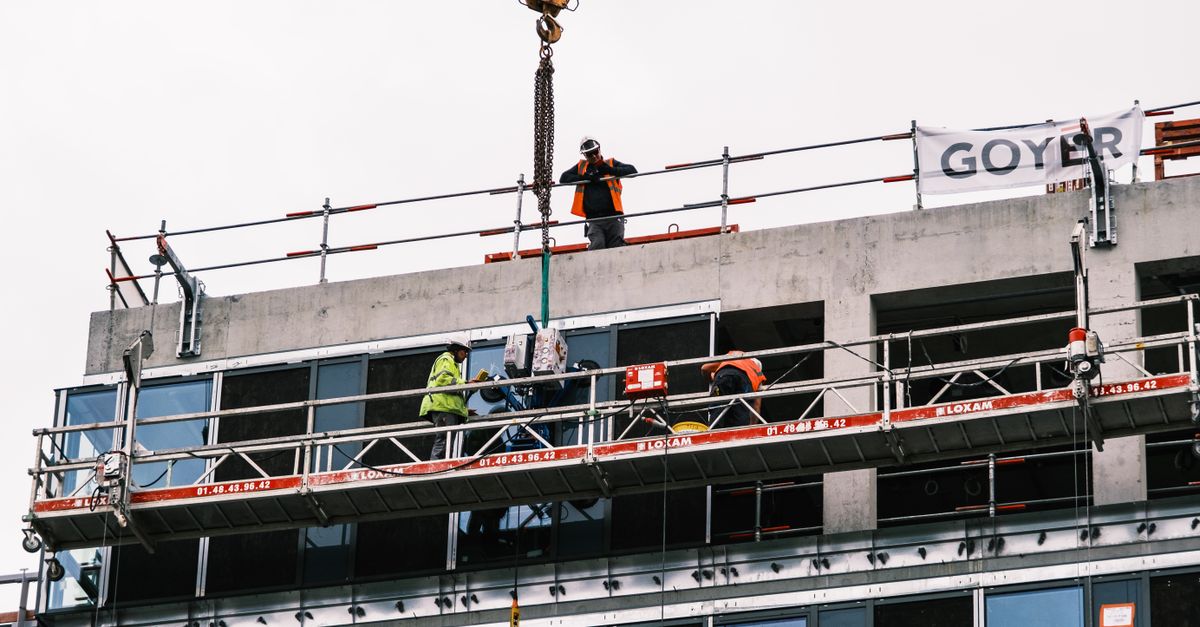 A construction site with workers using safety harnesses and helmets.