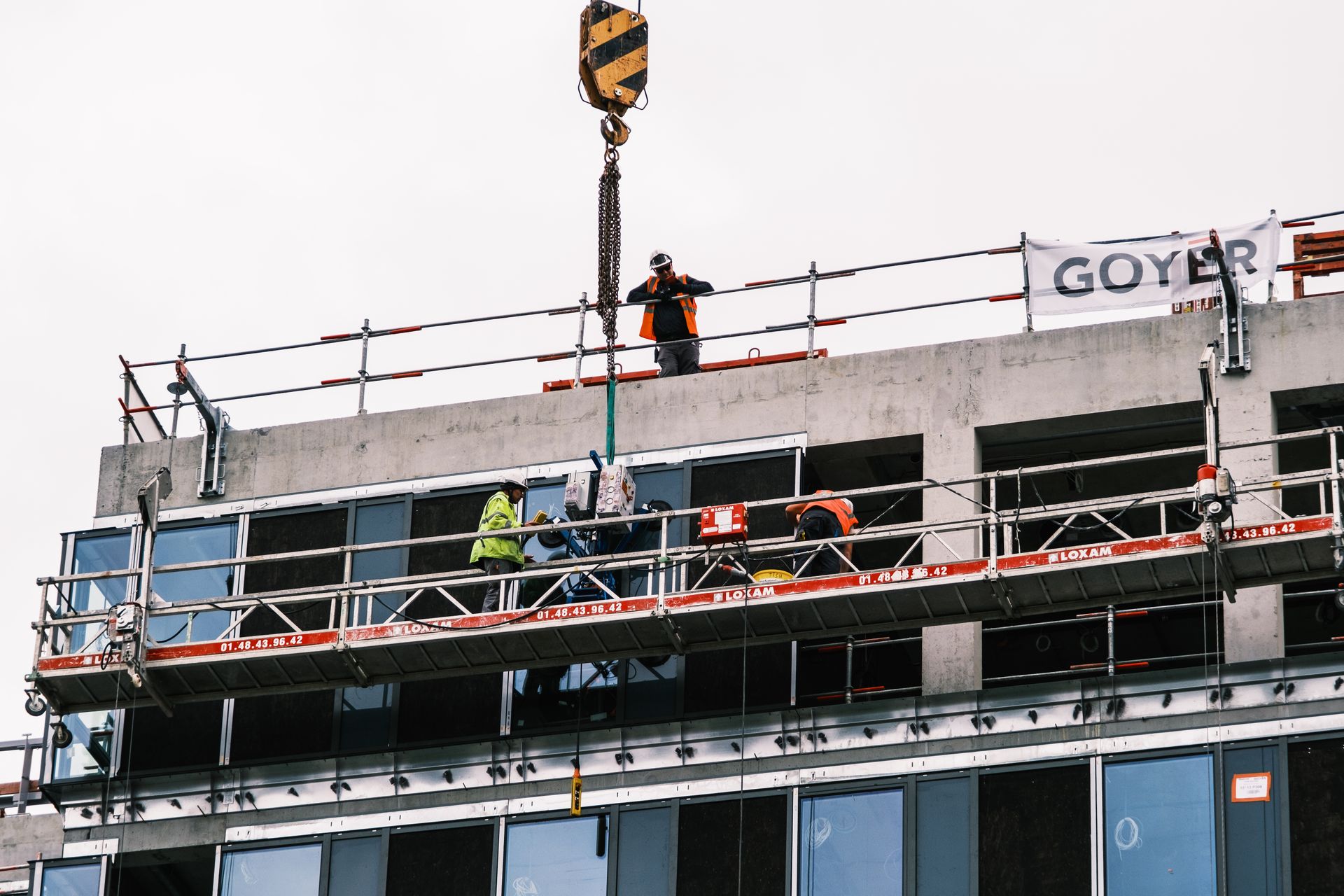Professional workers at a construction site managing equipment on a high-rise building.