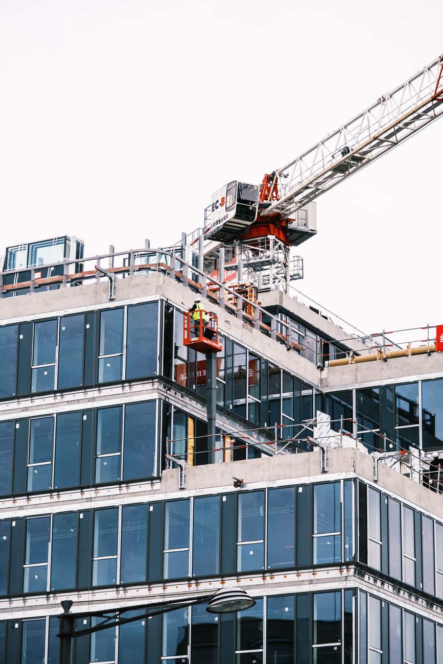 A construction site with a tower crane and modern glass building facade.