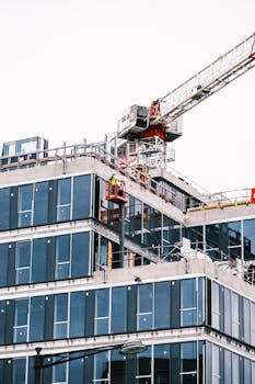 A construction site with a tower crane and modern glass building facade.