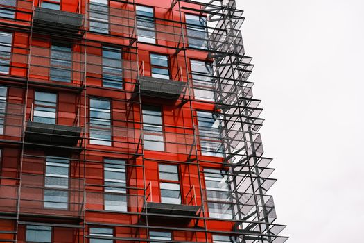 Close-up of a modern building with red facade and metal scaffolding.