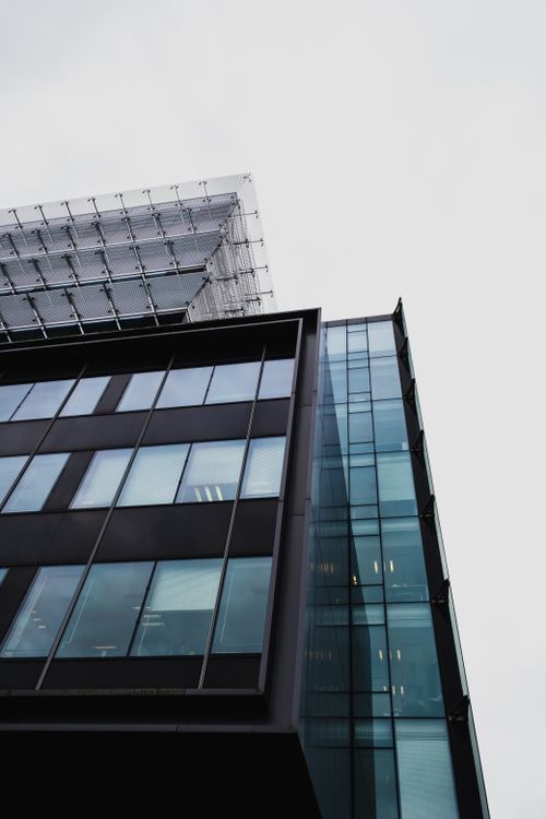 Free Low-angle view of a modern glass building with sleek architecture. Stock Photo