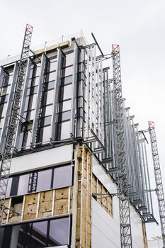 Low angle shot of a modern building under construction with glass windows and steel frames.
