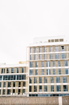 Contemporary multi-story building with glass and metal elements under a clear sky.