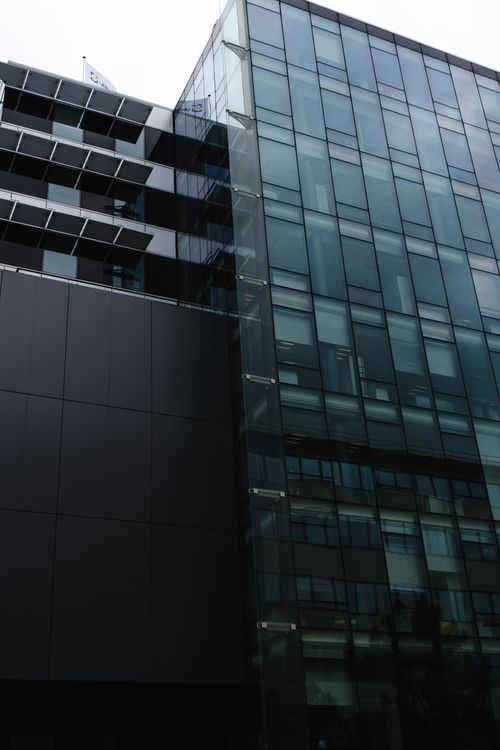 Free View of a modern glass building exterior with reflective windows and steel framework. Stock Photo