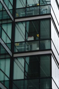 Close-up of a modern glass building facade reflecting the surroundings, showcasing architectural lines.