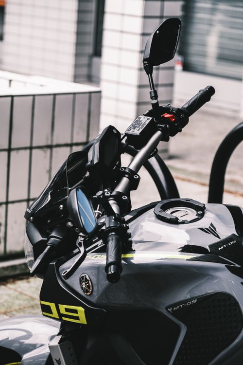 Free Detailed shot of a motorcycle handlebar in an urban setting, showcasing sleek design. Stock Photo