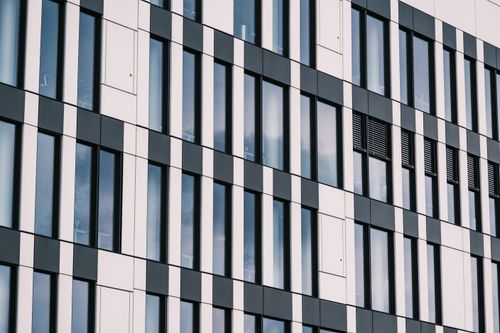 Free Abstract view of a modern office building with a reflective glass window facade. Stock Photo