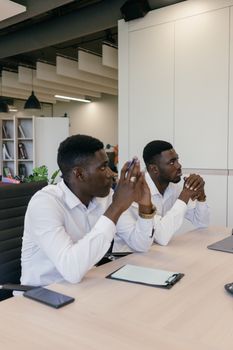 Two men in a modern office setting discussing business strategies during a meeting.