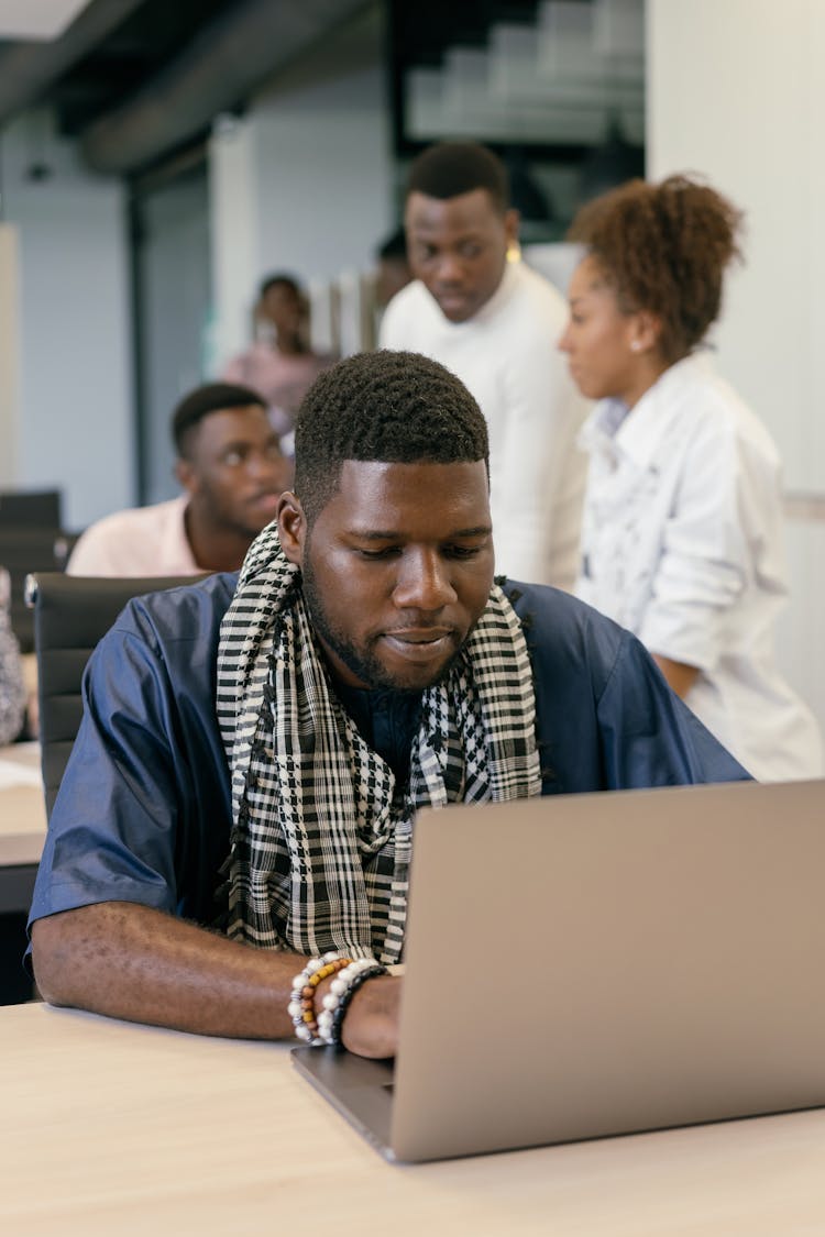 A Man Using A Laptop Sitting Behind His Desk