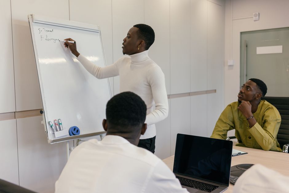 Three colleagues engaged in a brainstorming session using a whiteboard in a modern office. Three colleagues engaged in a brainstorming session using a whiteboard in a modern office.